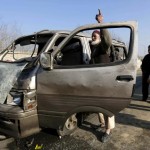 An Afghan man stands next to his damaged vehicle after a suicide attack in Kabul