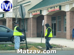 Workers restore a stop sign at Yussi's in West Gate.