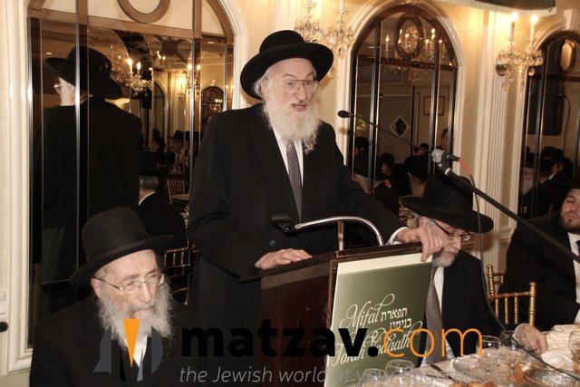 rav yisroel belsky speaking at previous mifal event and rav moshe wolfson on dais